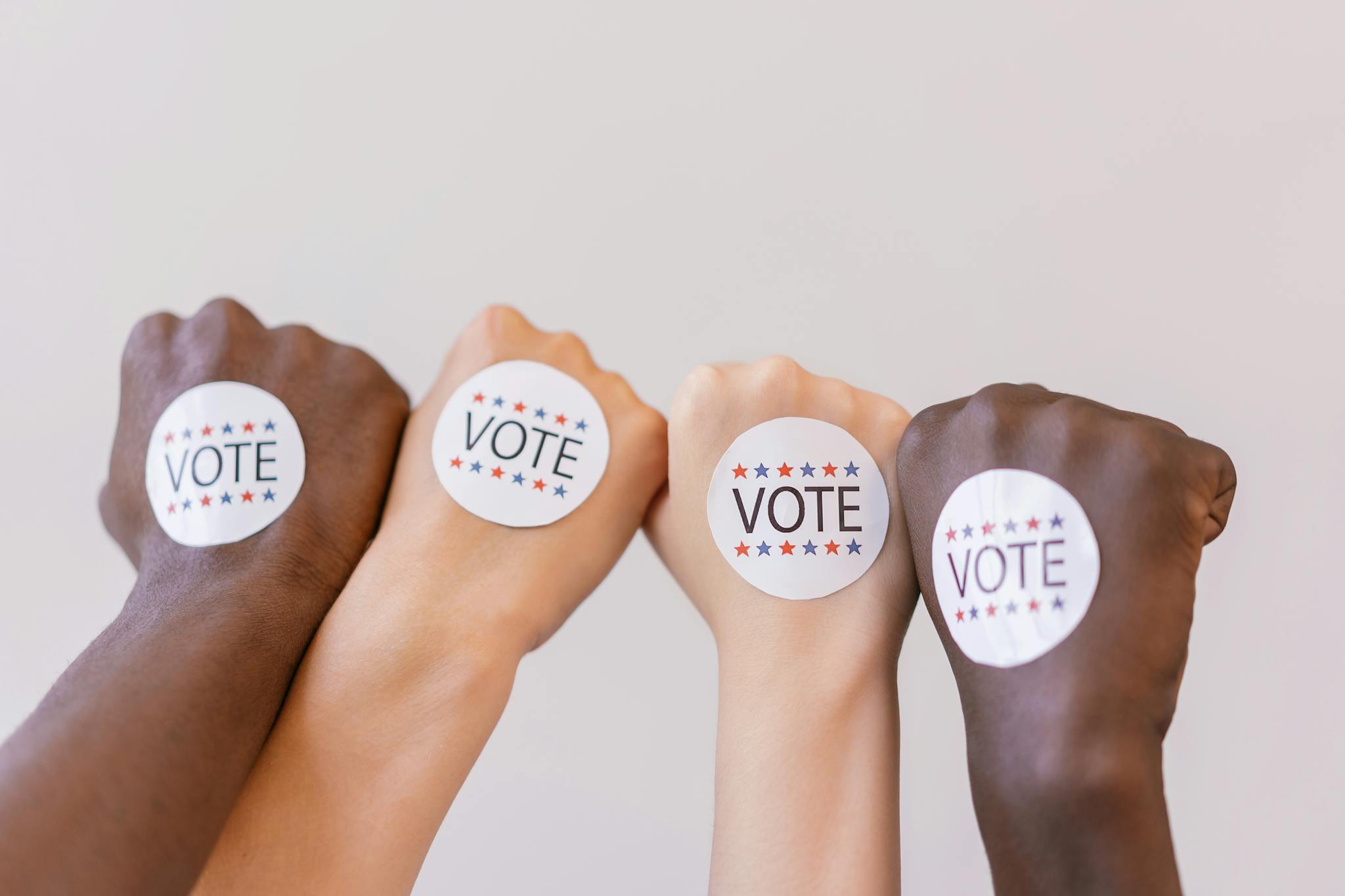 Close-up of diverse hands showing unity with vote stickers emphasizing democracy.