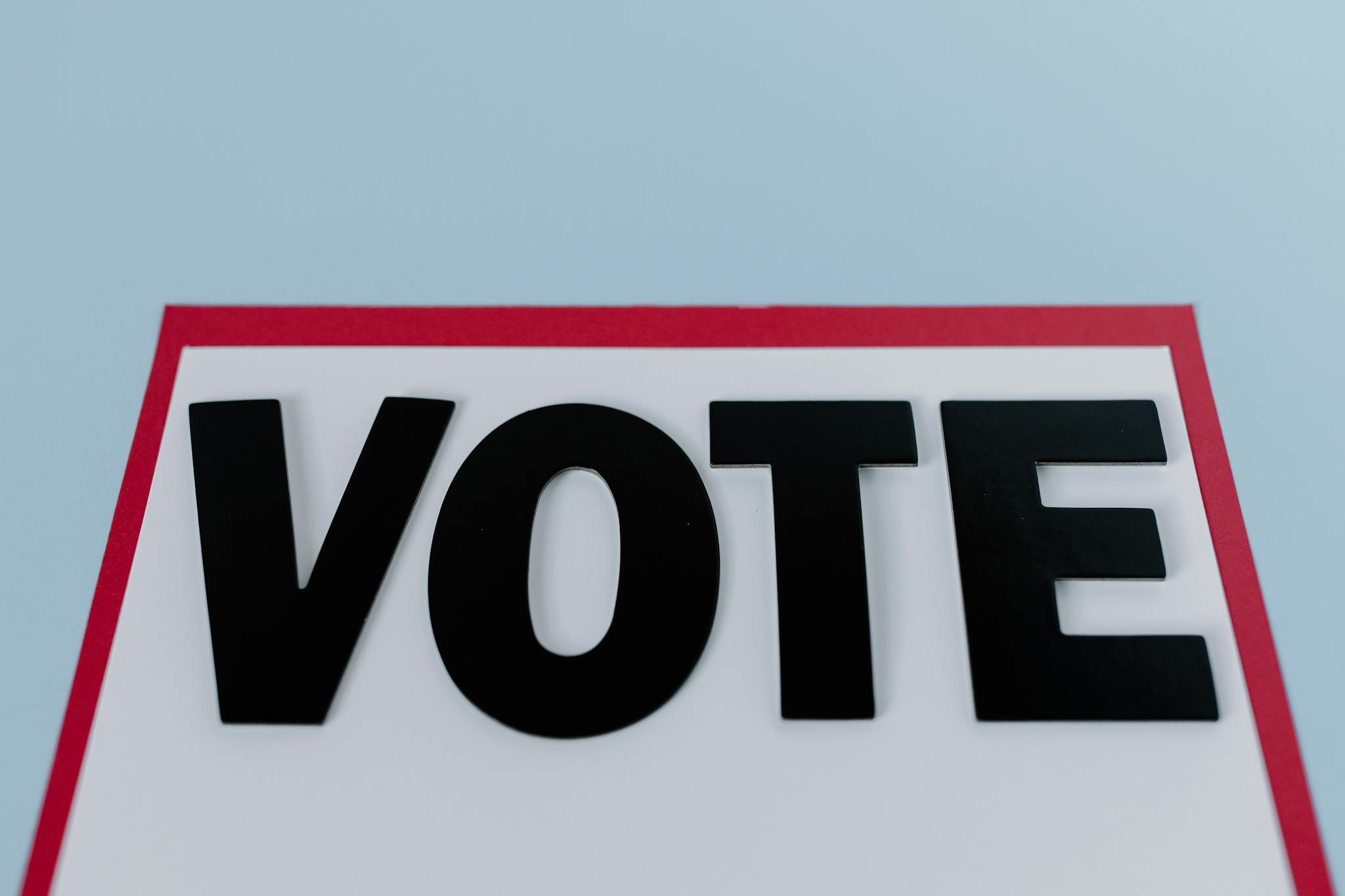 Sign with "VOTE" against a blue backdrop, highlighting political participation.